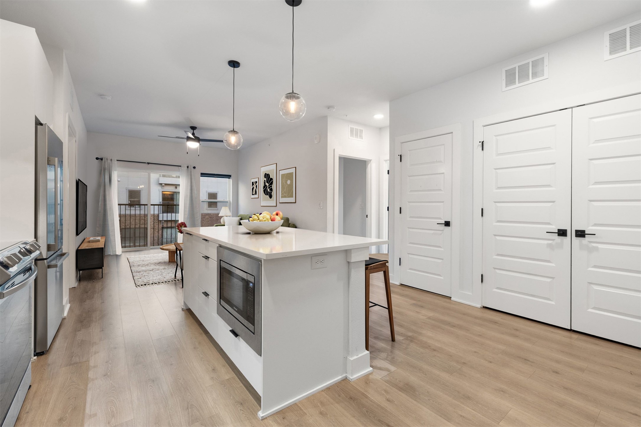 2500 Longview Street, Unit 418 Austin, TX 78705 - Photo 7 of 40 Kitchen with hanging light fixtures, a kitchen island, white cabinets, stainless steel appliances, and light wood-style floors