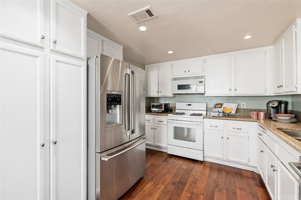 28825 Woodspring Circle Lake Forest, CA 92679 - Photo 12 of 50 a kitchen with white cabinets and stainless steel appliances