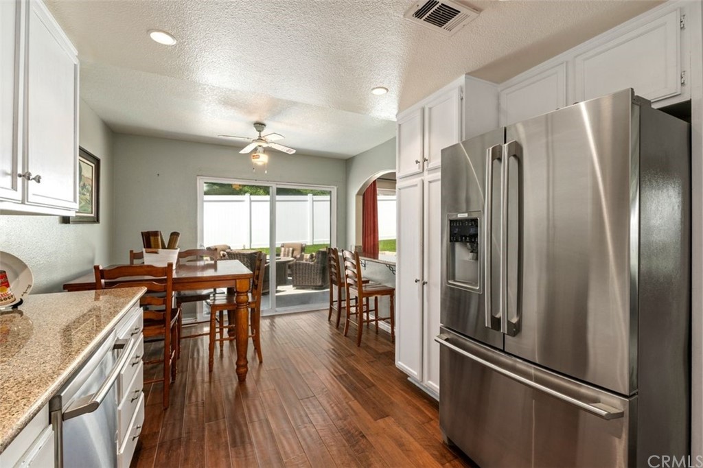 28825 Woodspring Circle Lake Forest, CA 92679 - Photo 13 of 50 a kitchen with stainless steel appliances granite countertop a refrigerator a sink dishwasher a dining table and chairs with wooden floor