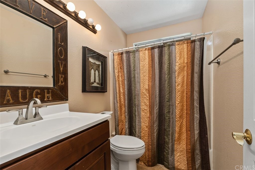 28825 Woodspring Circle Lake Forest, CA 92679 - Photo 25 of 50 a bathroom with a sink a toilet a mirror and shower curtain