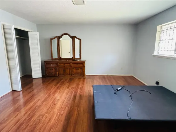an empty room with wooden floor furniture and a window
