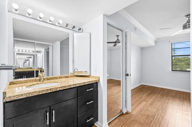 a bathroom with a granite countertop sink vanity mirror and shower