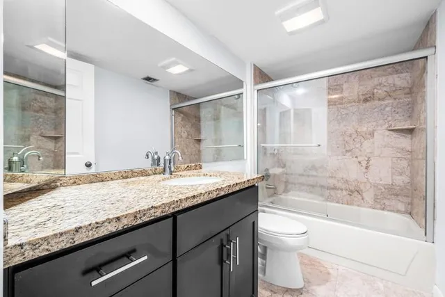 a bathroom with a granite countertop sink toilet mirror and bathtub