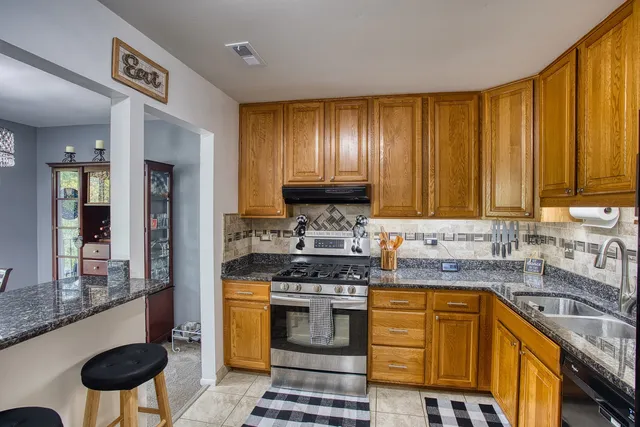 a kitchen with stainless steel appliances granite countertop a stove a sink and a microwave