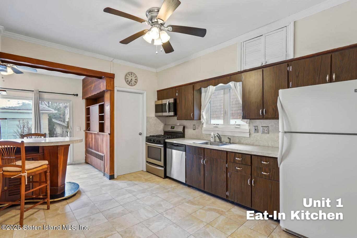 116 Silver Lake Road Staten Island, NY 10301 - Photo 14 of 36 a kitchen with stainless steel appliances a stove a refrigerator a sink a dining table and chairs with wooden floor