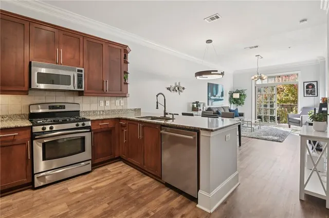 a kitchen with stainless steel appliances granite countertop a stove a sink and a microwave