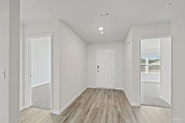 a view of a hallway with wooden floor and a bathroom