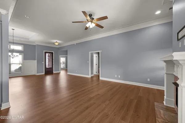 an empty room with wooden floor and a ceiling fan