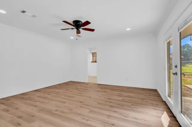 a view of empty room with wooden floor and fan