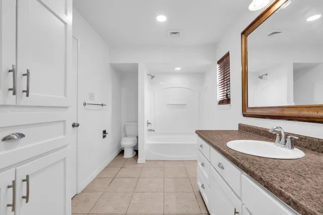 a bathroom with a granite countertop sink a mirror and a bathtub