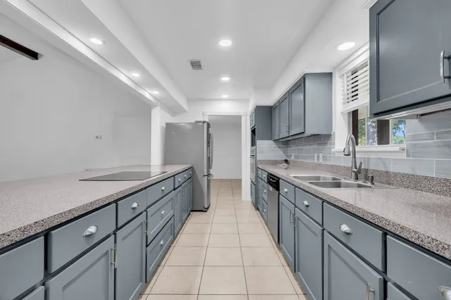a large kitchen with stainless steel appliances granite countertop a sink and cabinets