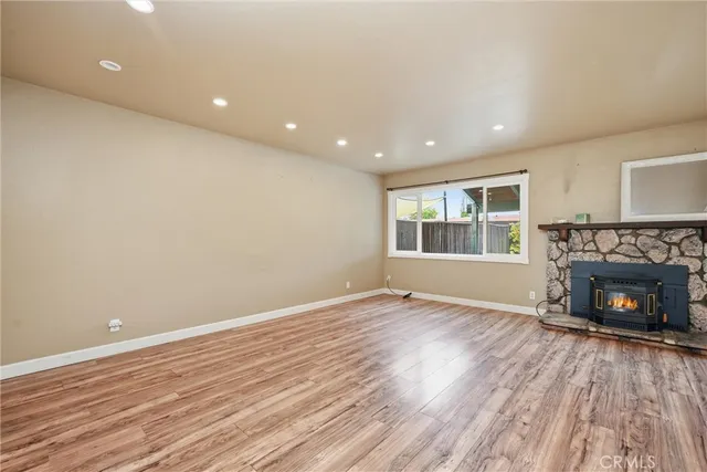 an empty room with wooden floor fireplace and windows