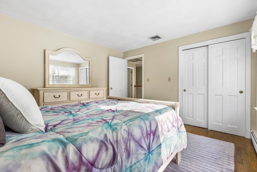 68 Sanborn Lane Reading, MA 01867 - Photo 24 of 42 a bedroom with a bed and a large mirror on dresser with wooden floor