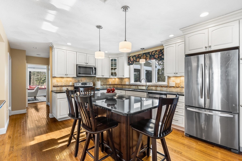 68 Sanborn Lane Reading, MA 01867 - Photo 5 of 42 a kitchen with stainless steel appliances granite countertop a dining table chairs refrigerator and microwave