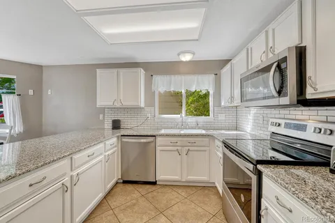 a kitchen with white cabinets and window