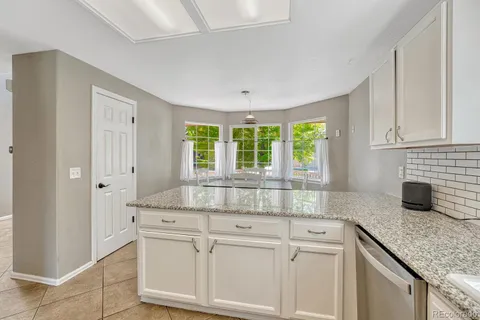 a kitchen with granite countertop a refrigerator stove and cabinets