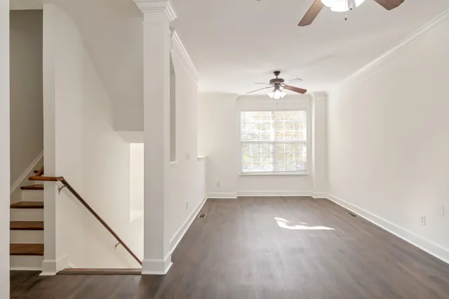 a view of an empty room with a window and wooden floor