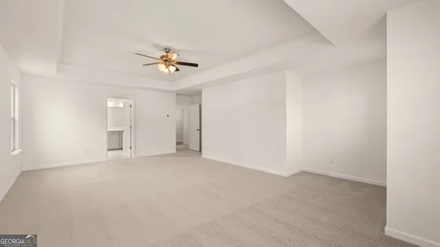 an empty room with chandelier fan and windows