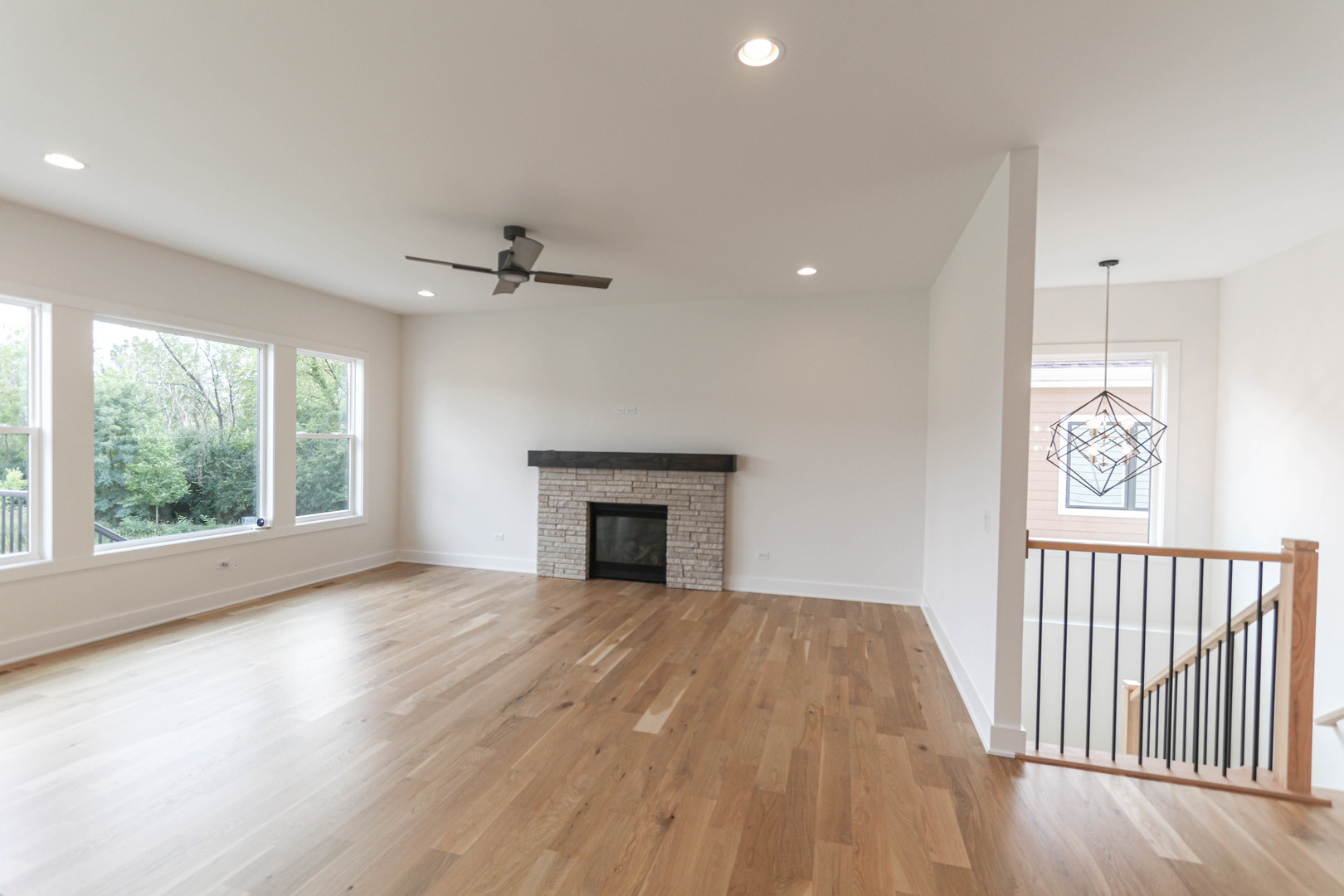 1033 Emerald Drive Naperville, IL 60540 - Photo 9 of 16 an empty room with windows a fireplace and a chandelier fan