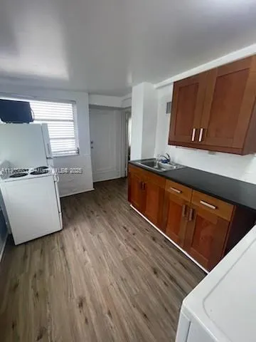 a kitchen with granite countertop wooden cabinets and a wooden floor