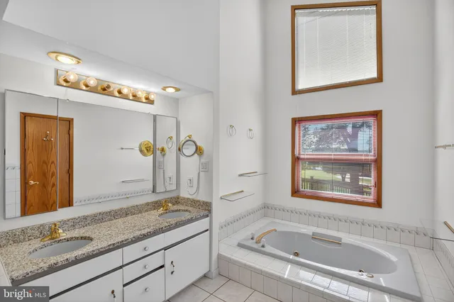 a bathroom with a granite countertop tub sink and mirror