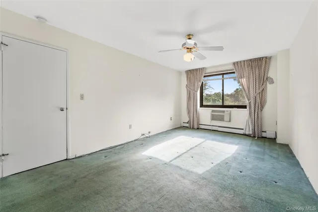 an empty room with chandelier fan and windows