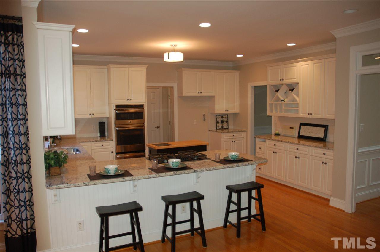 10900 Fitzwilliam Street Raleigh, NC 27614 - Photo 4 of 25 a kitchen with stainless steel appliances granite countertop a stove a refrigerator a sink a stove and white cabinets with wooden floor