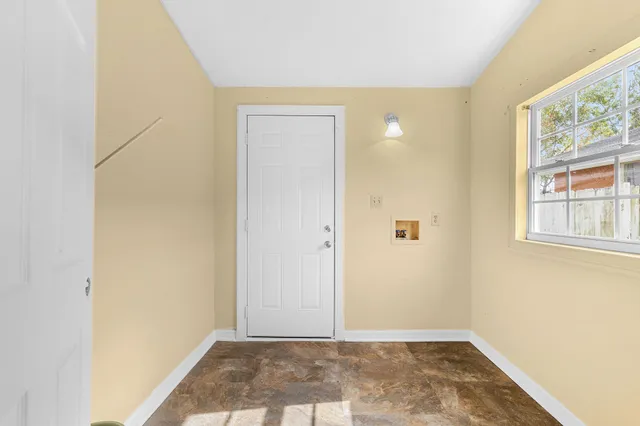 a view of an empty room with window and wooden floor