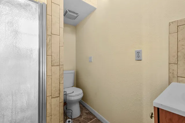 a bathroom with a granite countertop toilet and a sink