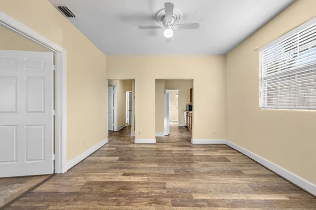 a view of an empty room with wooden floor and a window