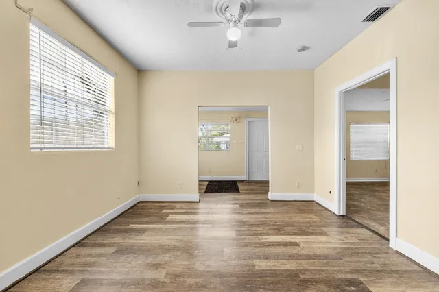 a view of an empty room with wooden floor and a window