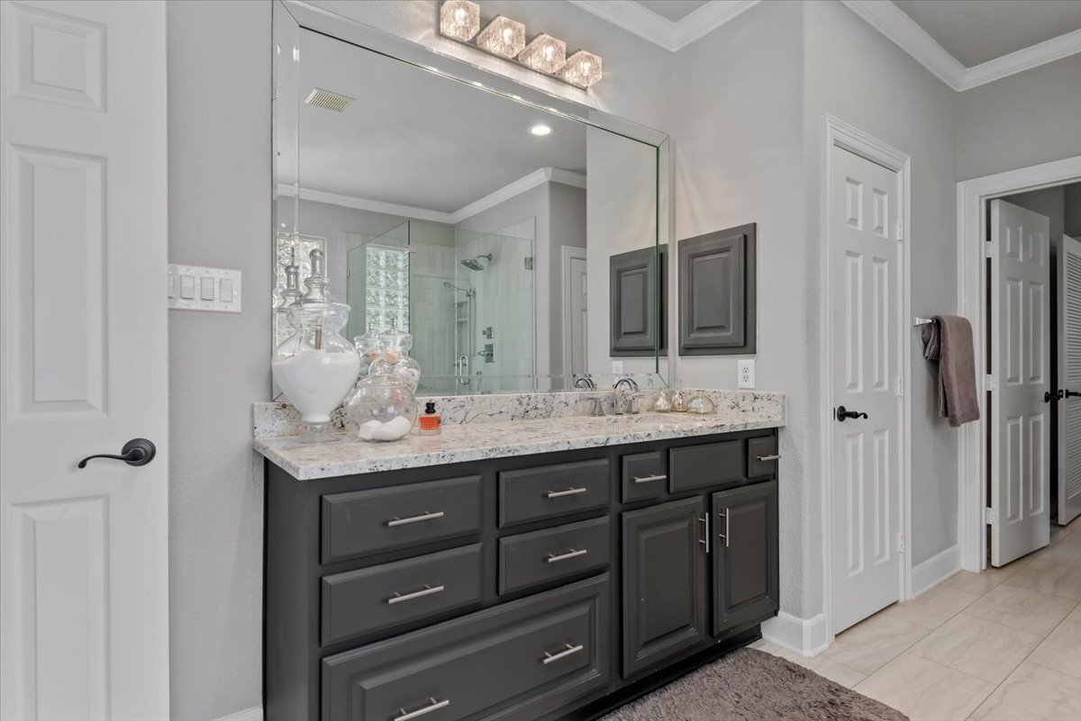 15519 Stallion Point Circle Cypress, TX 77429 - Photo 18 of 37 Bathroom featuring a dual vanity with a light-colored countertop and dark cabinetry, a large wall-mounted mirror, and overhead lighting