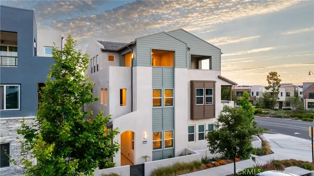 a front view of residential houses with yard and trees in the background