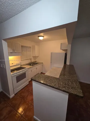 a kitchen with granite countertop white cabinets and white appliances
