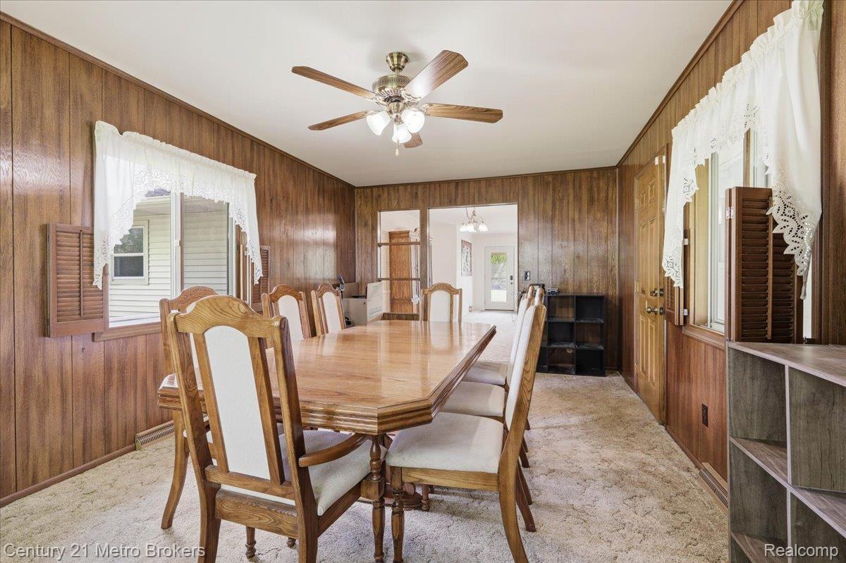 5457 North Seymour Road Flushing, MI 48433 - Photo 15 of 43 Carpeted dining space featuring ceiling fan and wood walls