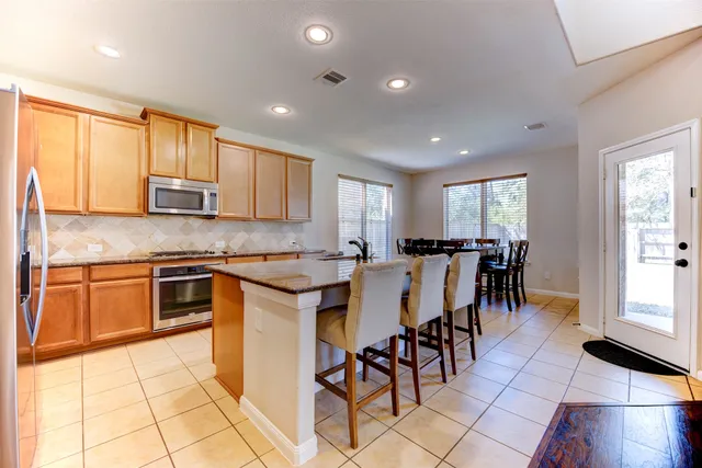 a kitchen with stainless steel appliances kitchen island granite countertop a stove a sink a dining table and chairs with wooden floor