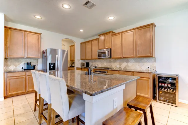 a kitchen with stainless steel appliances granite countertop a refrigerator a stove top oven and a sink with island