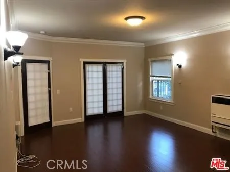 a view of an empty room with wooden floor and a window