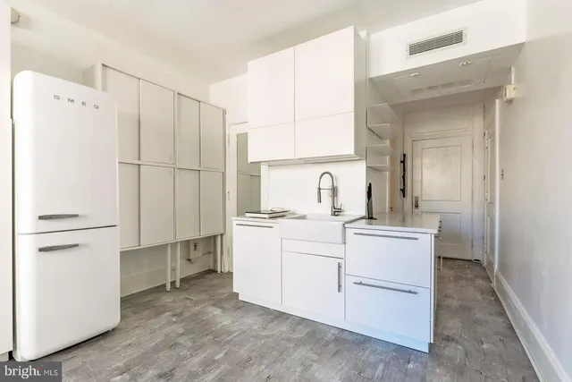 a room with a sink and white cabinets