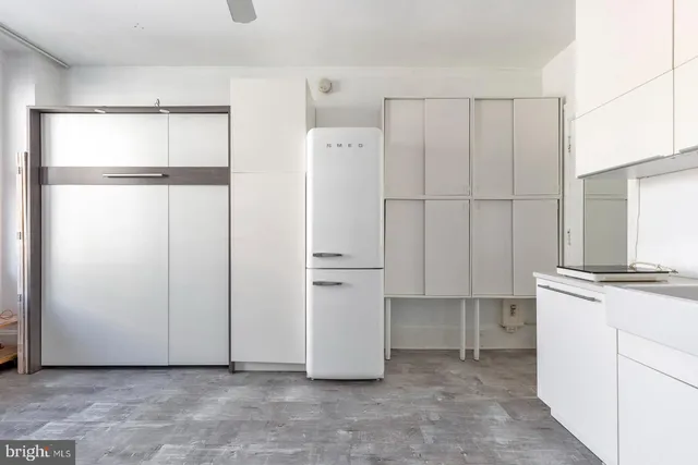 a view of a kitchen with refrigerator and white cabinets