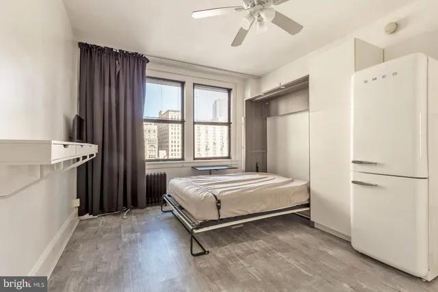 a spacious bedroom with a bed and a refrigerator