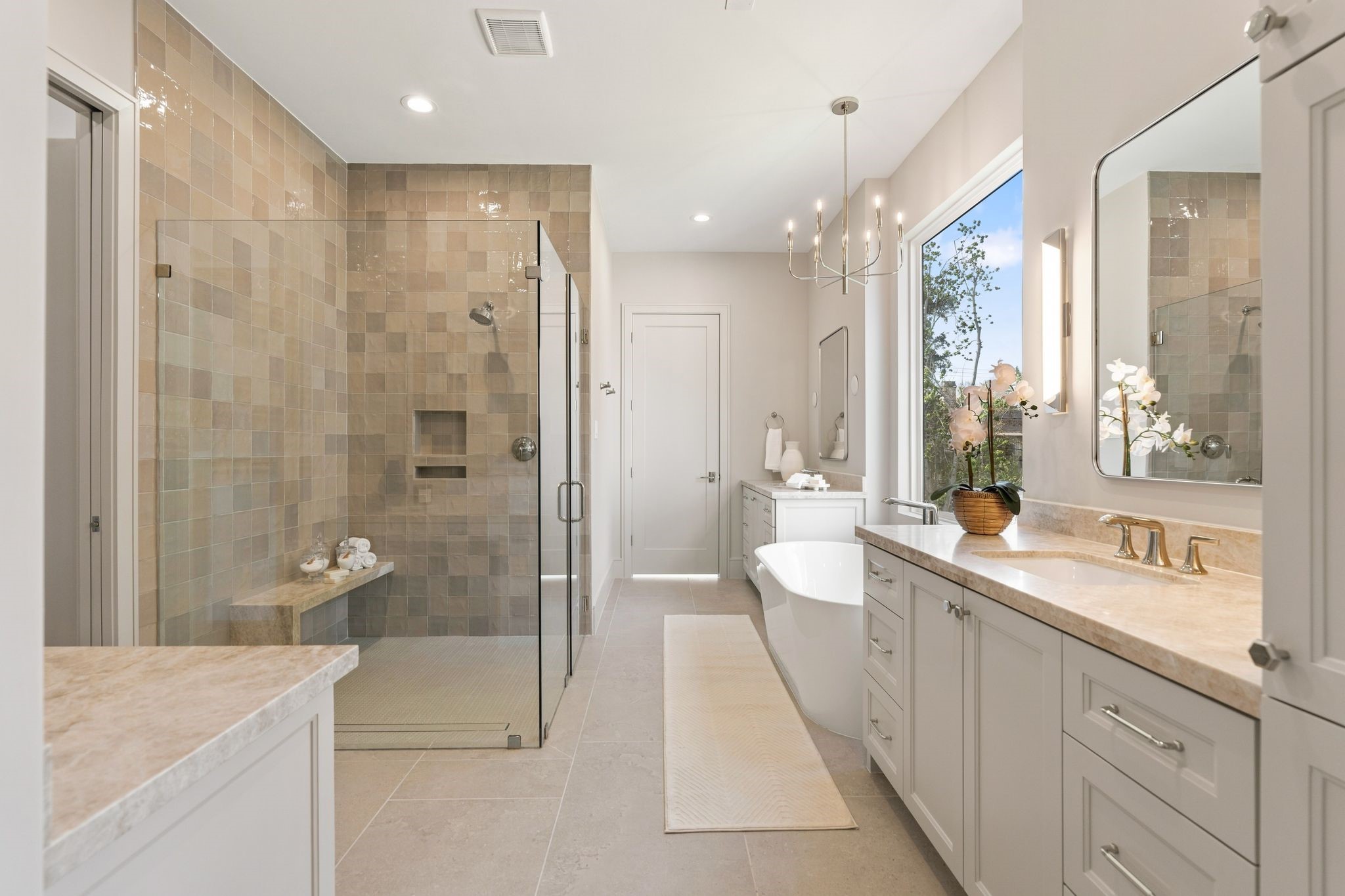 711 East 12th Street Houston, TX 77008 - Photo 30 of 47 Warm natural stone and soft lighting give the primary bath a serene, luxurious feel. Taj Mahal quartzite countertops pair with polished nickel Kohler Purist fixtures and glowing alabaster sconces. Double sinks provide convenience and ease both framed with alabaster sconces.