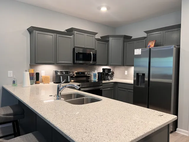 a kitchen with kitchen island a sink refrigerator and microwave