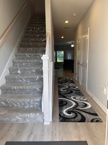 a view of a hallway with wooden floor and a bathroom