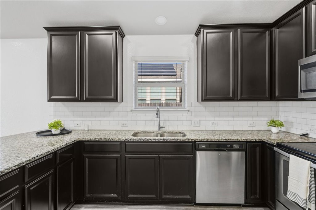 19040 Kimberlite Drive Pflugerville, TX 78660 - Photo 14 of 40 Kitchen featuring stainless steel appliances, light stone counters, recessed lighting, tasteful backsplash, and dark cabinets