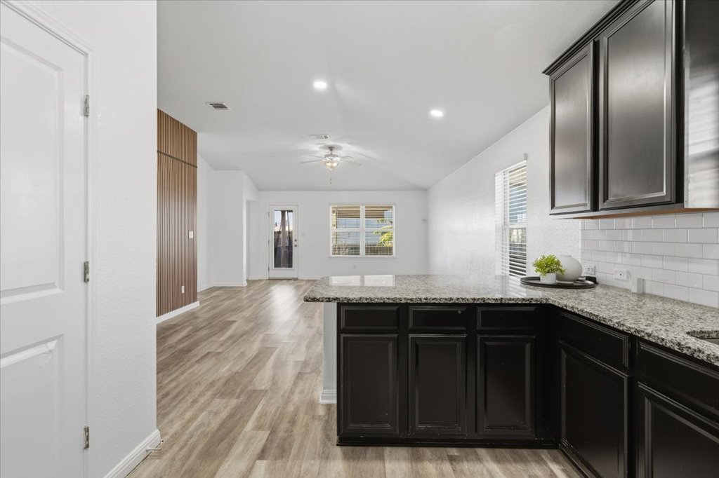 19040 Kimberlite Drive Pflugerville, TX 78660 - Photo 15 of 40 Kitchen featuring dark cabinetry, light stone counters, ceiling fan, tasteful backsplash, and light wood finished floors