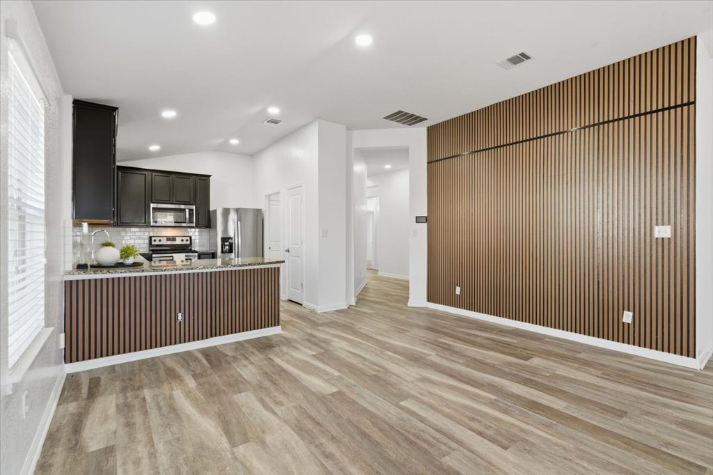 19040 Kimberlite Drive Pflugerville, TX 78660 - Photo 20 of 40 Kitchen featuring a peninsula, appliances with stainless steel finishes, vaulted ceiling, tasteful backsplash, and light wood-style flooring