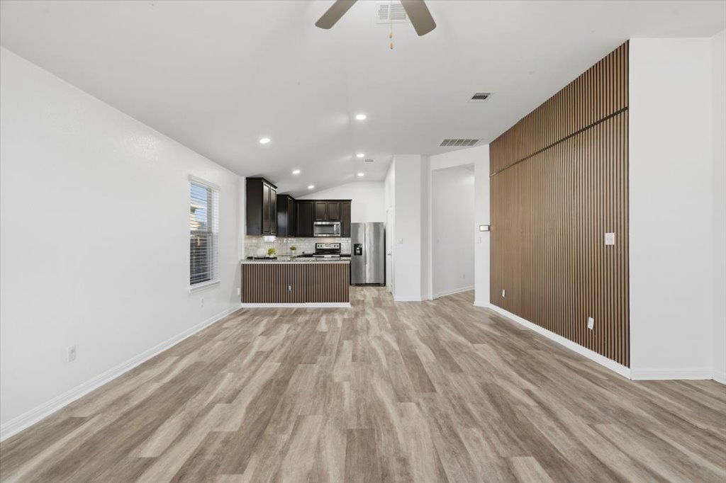 19040 Kimberlite Drive Pflugerville, TX 78660 - Photo 23 of 40 Unfurnished living room with ceiling fan, light wood-style floors, vaulted ceiling, and recessed lighting