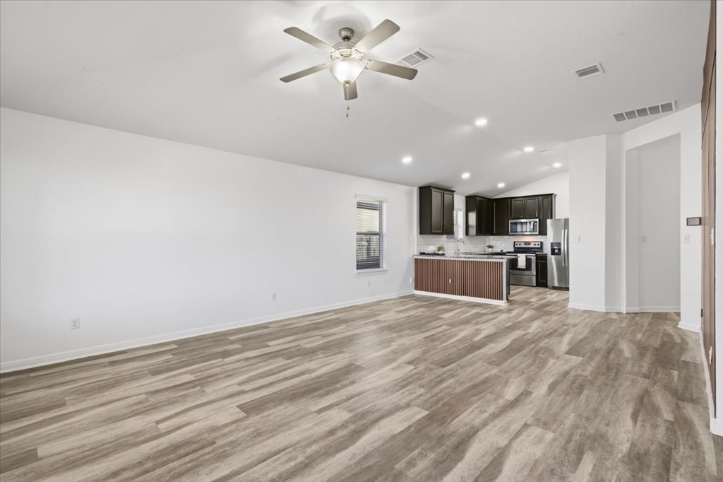 19040 Kimberlite Drive Pflugerville, TX 78660 - Photo 24 of 40 Unfurnished living room featuring lofted ceiling, ceiling fan, light wood finished floors, and recessed lighting