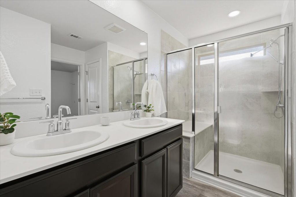 19040 Kimberlite Drive Pflugerville, TX 78660 - Photo 29 of 40 Full bath with a stall shower, double vanity, and light wood finished floors